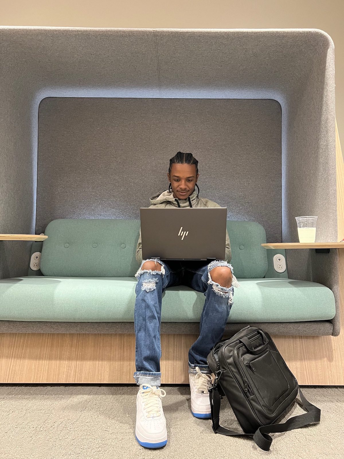 A man sitting on a couch working on a laptop computer.